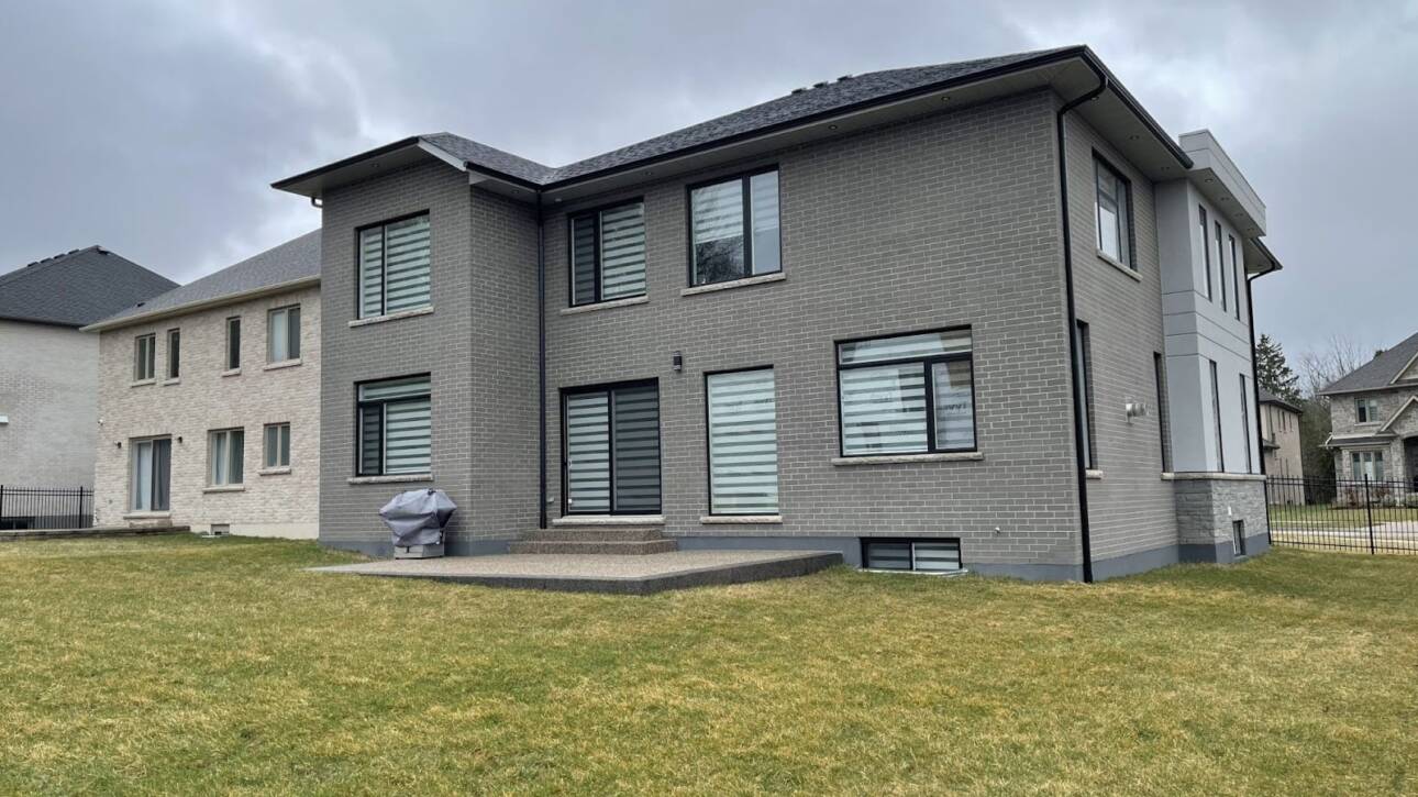 Side view of a grey brick house in Waterloo with old windows that could be replaced for efficiency