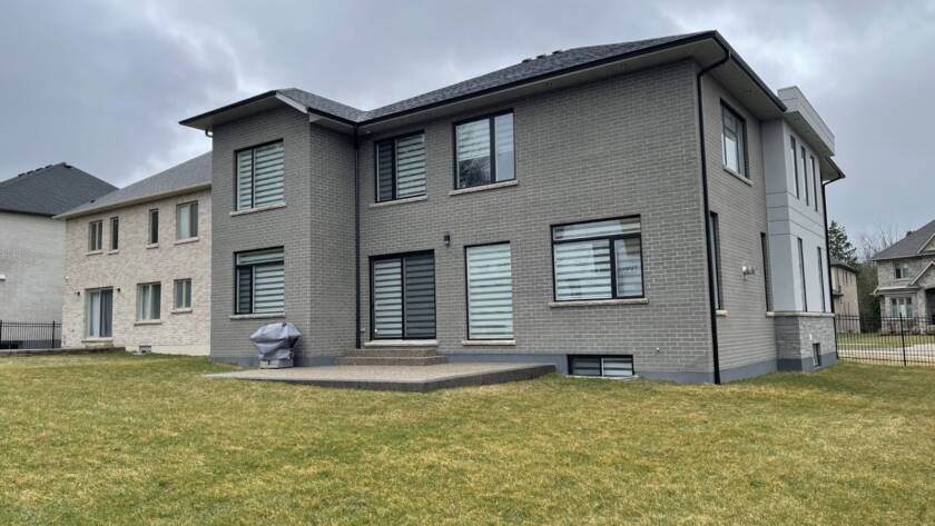 Side view of a grey brick house in Waterloo with old windows that could be replaced for efficiency